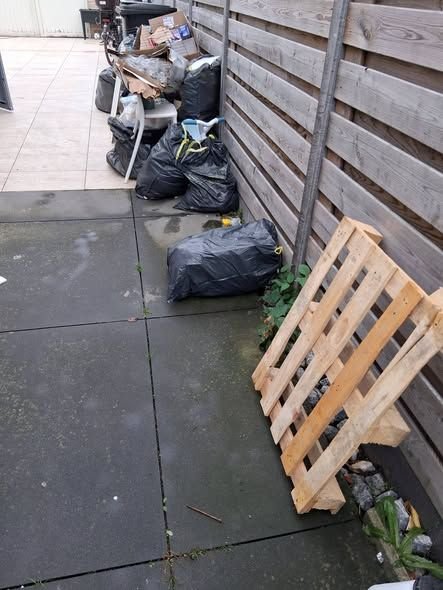 Terras met vuilniszakken en een houten pallet voor de opruiming